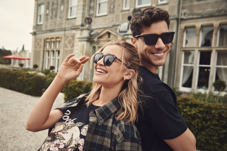 A cool looking man and woman standing back to back smiling